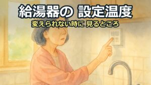 台所の壁のリモコンに手を伸ばし、温度が変わらず困った顔をしている50代の女性